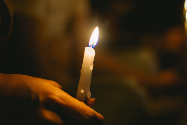 soft focus of people lighting candle vigil in darkness seeking h