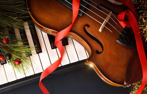 Fir tree branch with wooden note against blurred lights, space for text. Christmas music